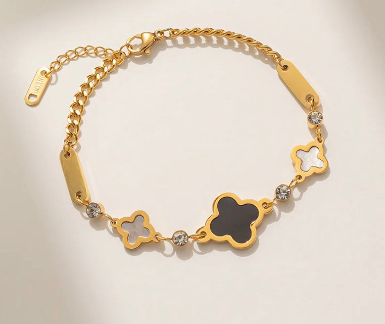 Gold bracelet with black and white clover charms